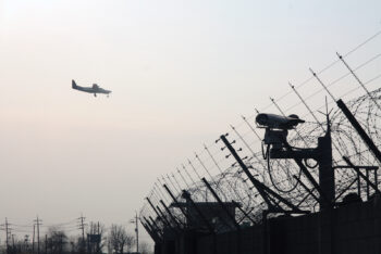 plane flying over barbed wall and security camera in gimpo airport, seoul.